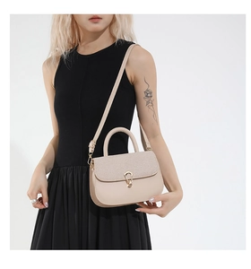 Detail of beige saddle bag showing mixed textures and golden U-shaped metal buckle