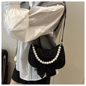 Detail of black crescent hobo bag with lace fabric, satin bow, and pearl handle