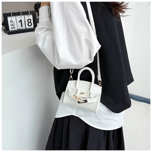 Close-up of white lychee pattern leather handbag with metallic buckle on a model
