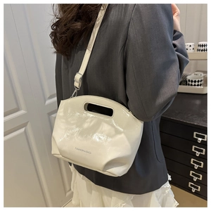 Detail of cream patent leather bucket bag with top handle and FASHION & BAGS lettering