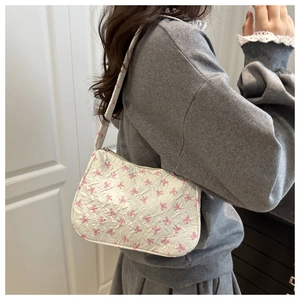 Detail of floral bow print on white shoulder bag with textured jacquard fabric