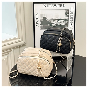 Detail of quilted crossbody bags with triple zip compartments and gold chain straps