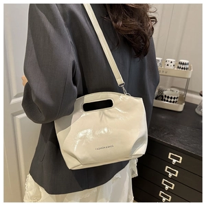 Detail of white patent leather shoulder bag with FASHION & BAGS print and carry handle