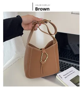 Détail du sac en cuir marron avec surpiqûres blanches et anneau en métal doré