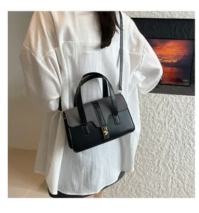 Détail d'un sac bicolore avec rabat en tissu gris et fermoir tournant en métal doré