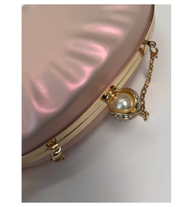 Macro detail of pink satin shell bag with pearl metal clasp and crystal embellishments