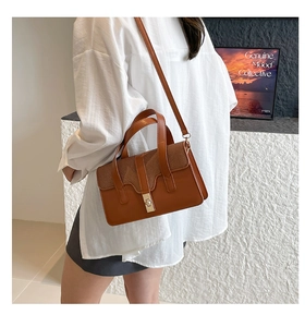 Détail latéral d'un sac à main marron avec fermoir doré porté par un mannequin