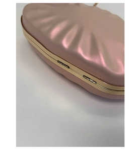 Detail of pink pearl evening bag featuring pleated texture and gold metal frame closure