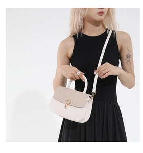 Detail view of cream crossbody bag featuring woven flap and gold metal twist lock buckle