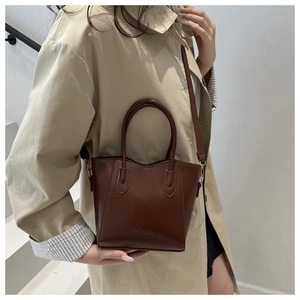 Détail d'un sac seau en cuir marron avec logo FASHION embossé et bandoulière réglable