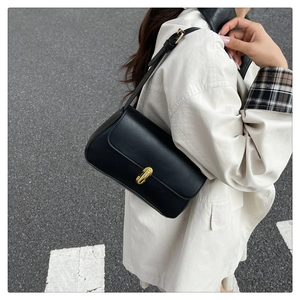 Detail of black underarm bag with gold metal twist lock and adjustable shoulder strap