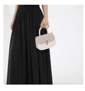 Détail du sac à rabat crème avec texture scintillante et fermoir fer à cheval doré