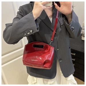 Model wearing a bright red patent leather handbag with FASHION & BAGS logo and chain strap