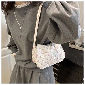 Detailed close-up of white floral baguette bag with pink bow patterns and metal zipper