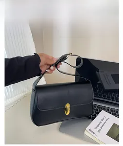 Detailed close-up of matte black leather handbag with a sleek golden oval twist lock clasp