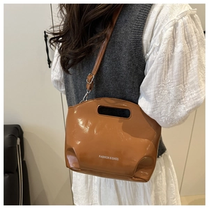 Detail of caramel glossy leather bag featuring Fashion & Bags logo and top handle