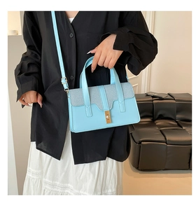 Détail du sac bandoulière bleu clair avec rabat tissé et boucle en métal doré