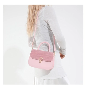 Detail view of pink saddle bag featuring woven texture flap and golden water-drop lock