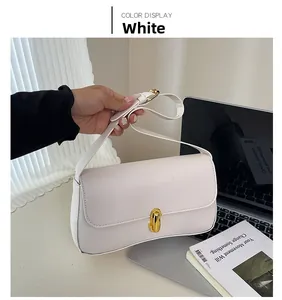 Close-up of white envelope shoulder bag featuring a golden metallic twist lock closure