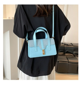 Sac à main bleu clair à rayures à la mode porté à l'épaule par une femme élégante