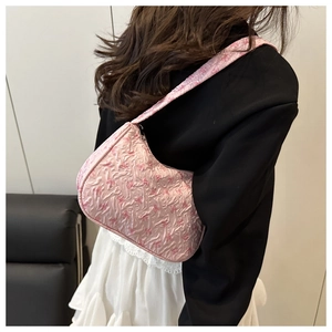 Detailed back view of pink bow pattern hobo bag worn with white skirt and black blazer