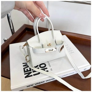Detail of white lychee leather texture and golden clasp on mini Kelly style handbag