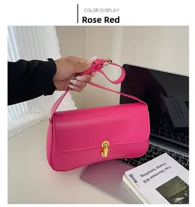 Detail of rose red glossy leather shoulder bag featuring a gold saddle swivel lock