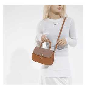 Détail du rabat tissé et cuir marron lisse sur sac bandoulière avec boucle dorée