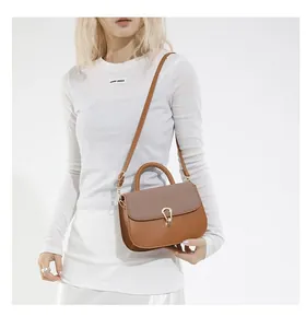 Detail of brown woven faux leather saddle bag with golden clasp and adjustable strap