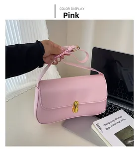 Detail of pink PU leather underarm bag featuring a gold twist lock and adjustable strap