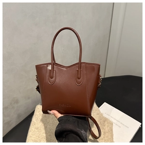 Détail d'un sac seau en cuir PU marron avec lettrage FASHION et finitions dorées chic