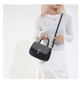 Detalle de bolso bandolera negro con cierre de herradura dorado en modelo de estudio