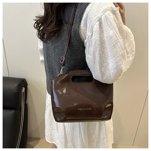 Detail of glossy dark brown tote bag showing the fashion logo and versatile shoulder strap