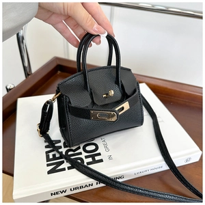Close-up of black litchi leather mini handbag with gold lock and sleek shoulder strap