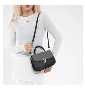 Detail of black crossbody bag with grey textured flap and golden irregular metal lock