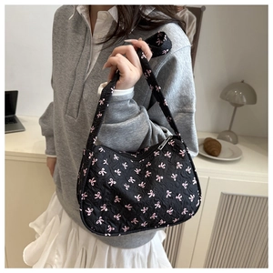 Detail view of black quilted shoulder bag featuring delicate pink bow embroidery