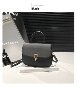 Detail of a black crossbody bag featuring a woven grey flap and golden U-shaped buckle