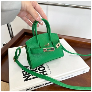 Macro view of bright green litchi texture leather handbag with gold metal clasp