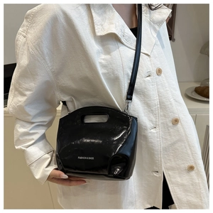 Close-up of black glossy handbag featuring FASHION & BAGS text and metal buckle detail