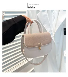 Detail of a creamy white handbag with striped fabric texture and gold U-shaped metal clasp