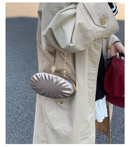 Champagne shell clutch with pearl clasp detail worn with a trench coat in street style