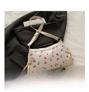 Detail view of cherry print small handbag next to a phone to show capacity and size