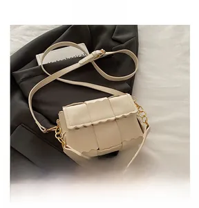 Detail of woven square handbag with wavy edge flap and gold chain strap accent