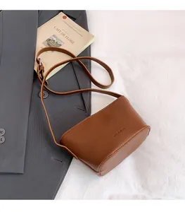 Detail of caramel brown litchi grain crossbody bag with Fashion embossing and strap