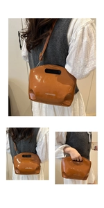 Detail of glossy brown chain handbag with white fashion lettering and adjustable strap