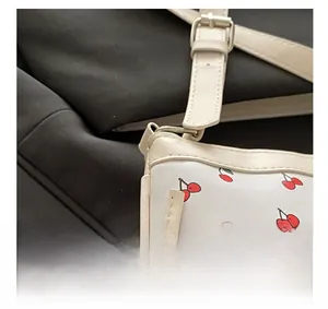 Detail of adjustable silver buckle and cherry print on white leather shoulder strap