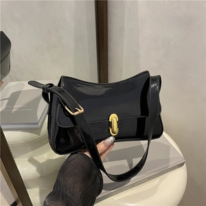 Glossy black patent leather underarm bag with gold capsule lock in handheld view
