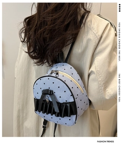 Detail of blue striped mini backpack with black bow and heart pendant on model