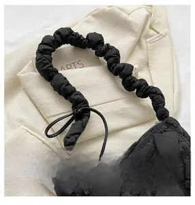 Close-up of black quilted cloud bag with ruffled shoulder strap and fabric texture