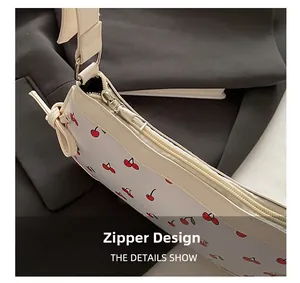 Close-up of secure metal zipper and red cherry print on white leather shoulder bag